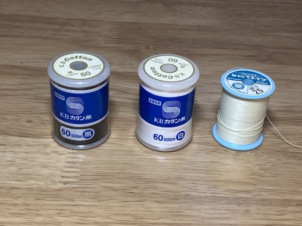 手芸品店で買えたカタン糸（白、黒）と、大きさの比較のためのシャッペスパン（ポリエステル糸）